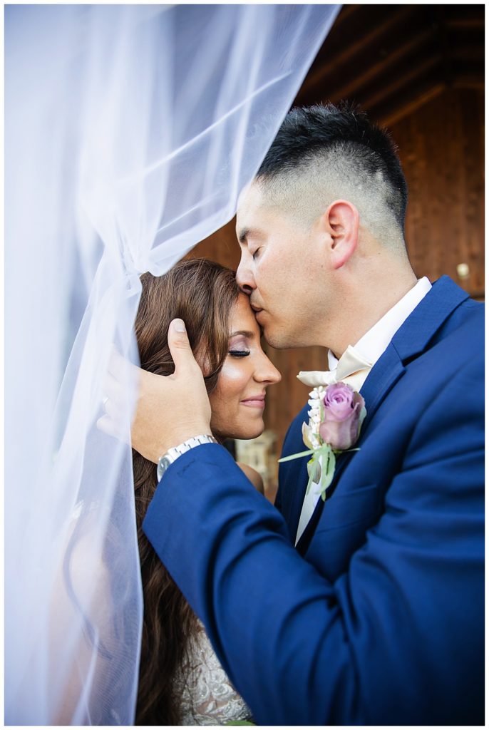 Groom kissing bride on forehead at Lucky Spur Ranch 